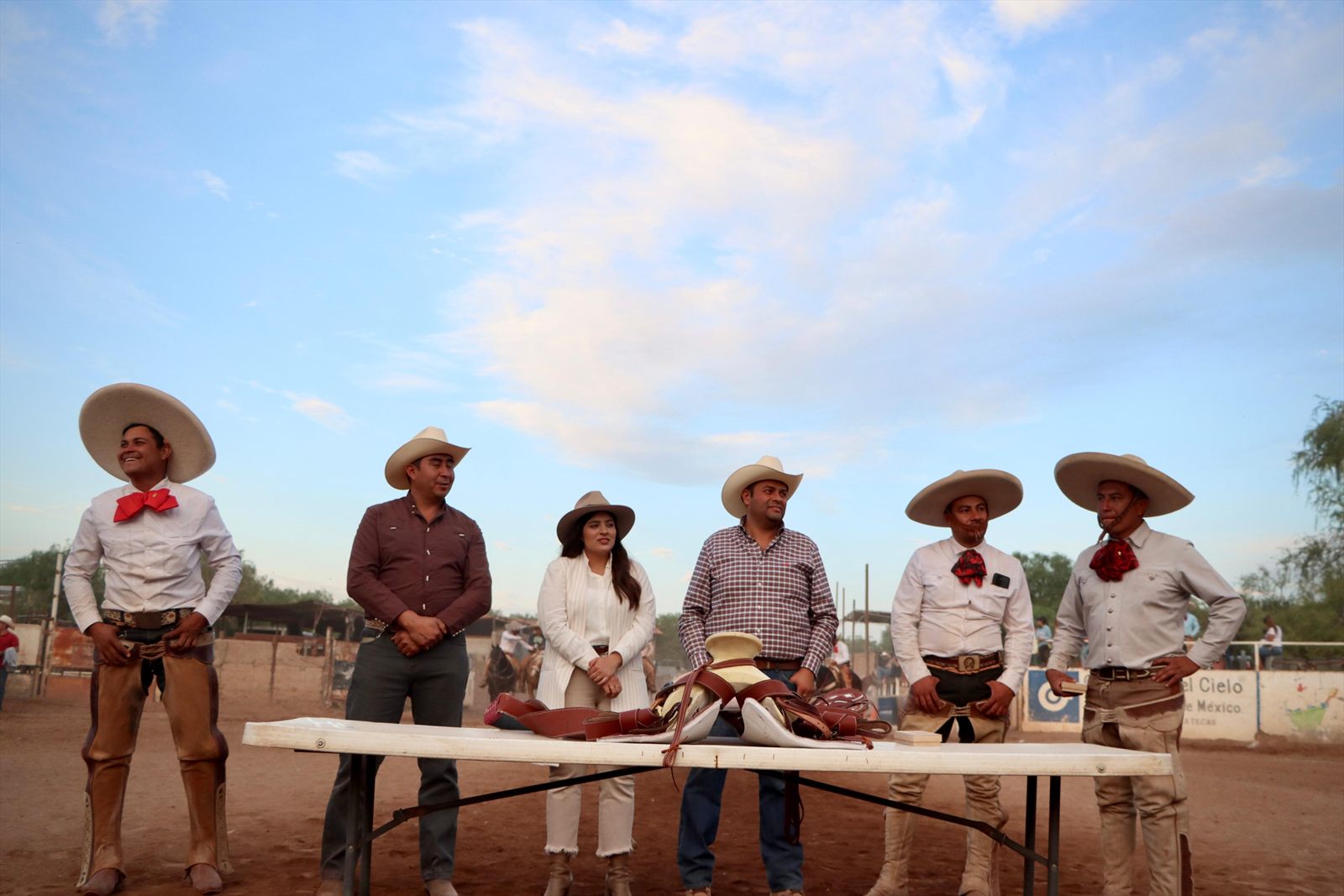 Premiación de una charreada al aire libre, con el equipo charro formado junto a la mesa
