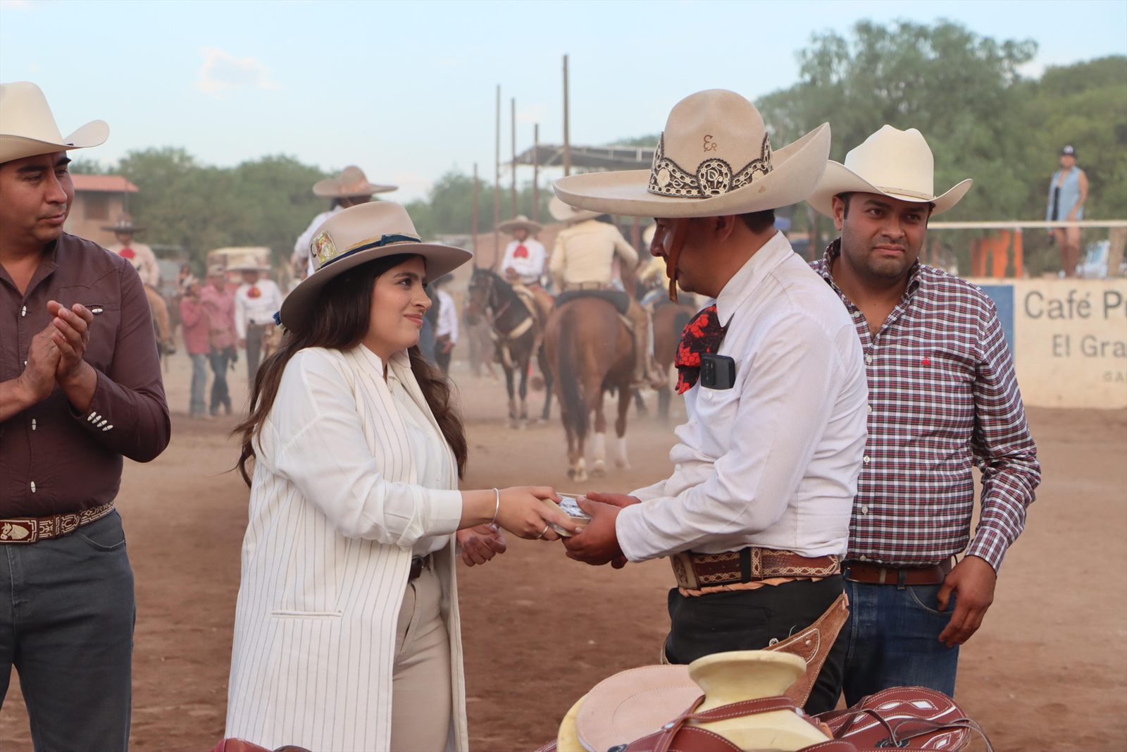 Entrega de un reconocimiento en el lienzo charro, con caballos al fondo