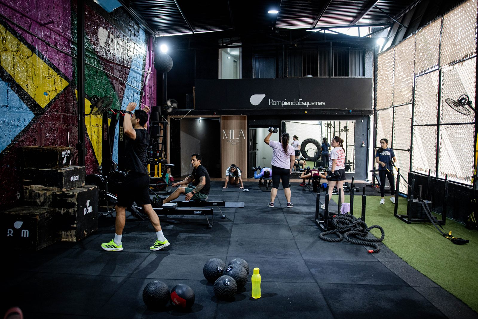 Interior del gimnasio ROM durante un entrenamiento, con el mural de colores al fondo