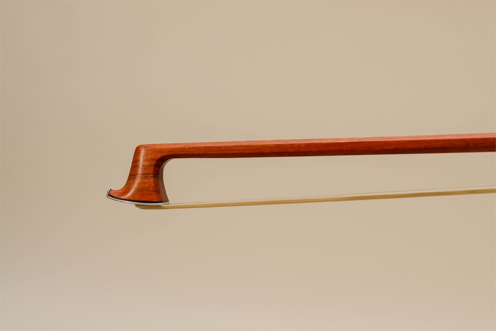 Detalle de un arco de violín sobre fondo beige