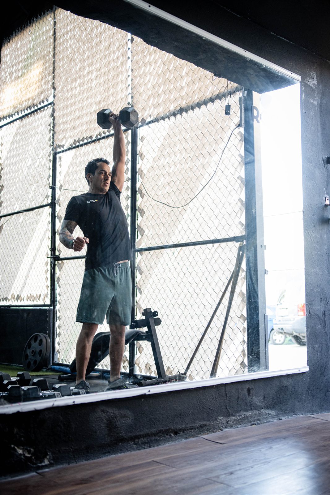 Entrenamiento en el gimnasio ROM: levantamiento de mancuerna junto al ventanal