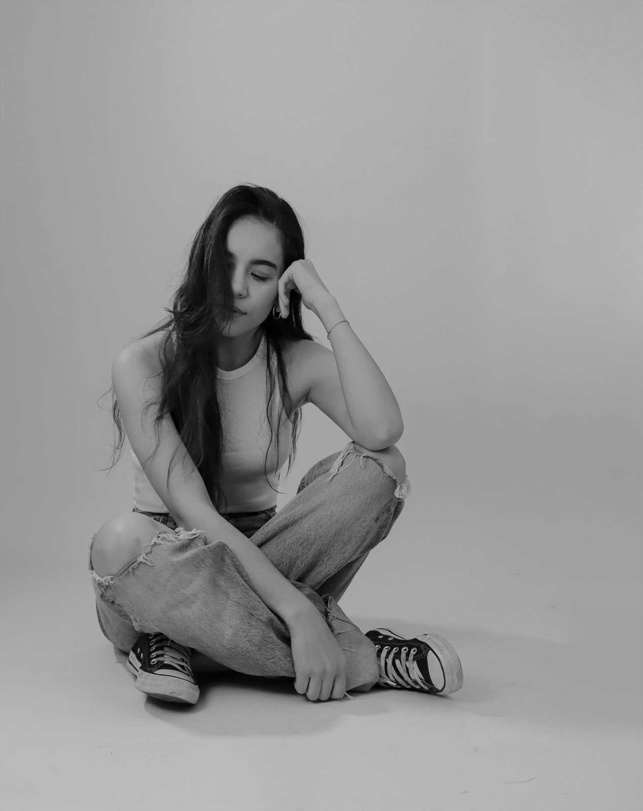 Retrato de estudio en blanco y negro, sentado con la mano en el rostro
